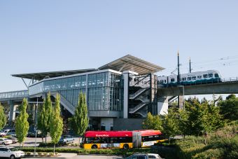 Link light rail station from a distance with a King County Metro bus in the foreground near the station.